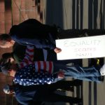 A Patriot Prayer rallier wearing an American flag jacket reaches toward a counter-protesting gentleman holding a poster that reads "Equality scares Nazis".